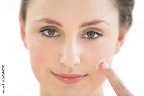 Photo: Beautiful young woman applying cream to her face Beautiful young woman applying cream to her face