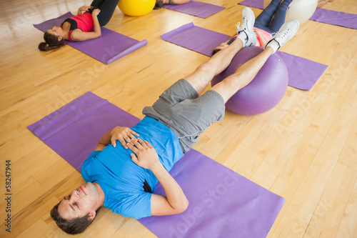 Photo: Class exercising with fitness balls at a bright gym Class exercising with fitness balls at a bright gym