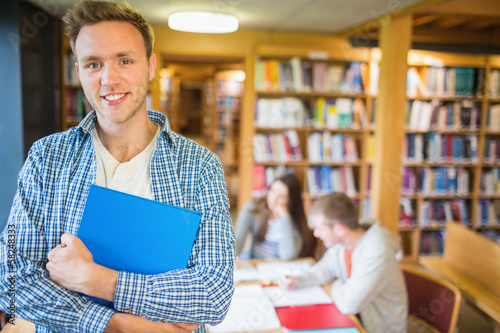 Photo: Male student with others in background at library Male student with others in background at library