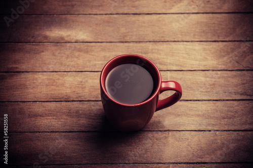 Photo: Red cup of coffee on wooden table Red cup of coffee on wooden table