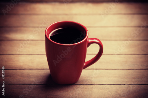 Photo: Red cup of coffee on wooden table Red cup of coffee on wooden table