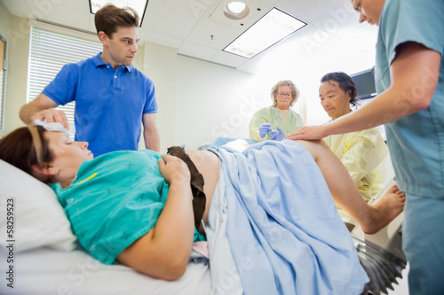 Photo: Man Looking At Medical Team Operating Pregnant Woman Man Looking At Medical Team Operating Pregnant Woman