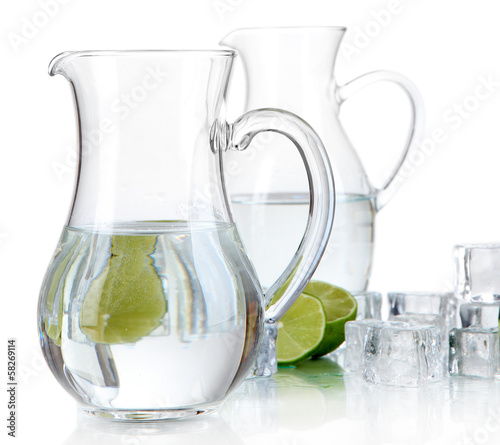 Photo: Glass pitchers of water with ice and lime isolated on white Glass pitchers of water with ice and lime isolated on white