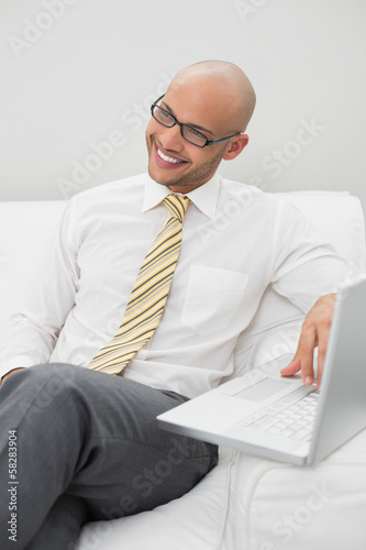 Photo: Businessman using laptop on sofa at home Businessman using laptop on sofa at home