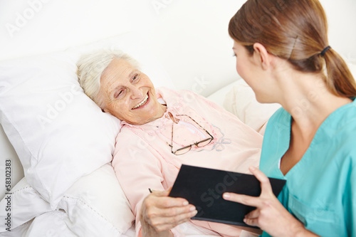 Photo: Krankenpflegerin liest Seniorin Buch vor Krankenpflegerin liest Seniorin Buch vor