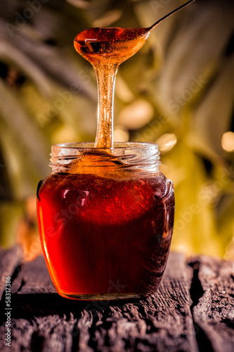 Photo: Honey drip in jar on the table Honey drip in jar on the table