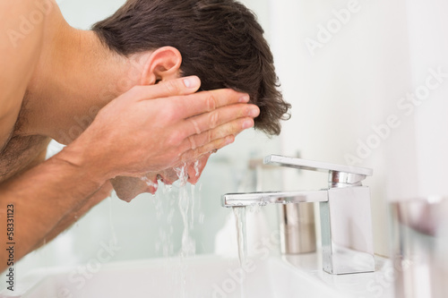 Photo: Shirtless young man washing face in bathroom Shirtless young man washing face in bathroom