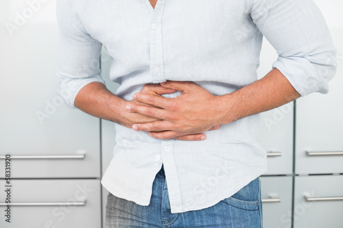Photo: Mid section of man suffering from stomach pain Mid section of man suffering from stomach pain