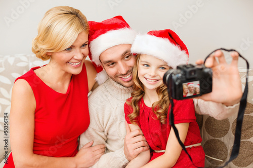 Photo: smiling family in santa helper hats taking picture smiling family in santa helper hats taking picture