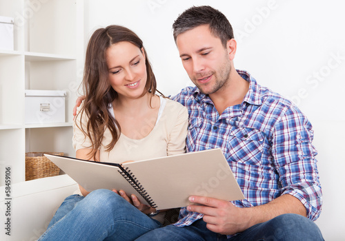 Photo: Couple Sitting On Couch Looking At Photo Album Couple Sitting On Couch Looking At Photo Album