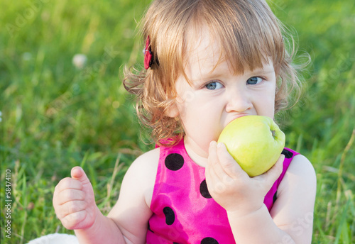 Photo: little girl is holding green apple little girl is holding green apple