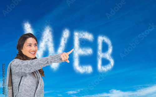 Photo: Composite image of smiling brunette wearing winter clothes point Composite image of smiling brunette wearing winter clothes point