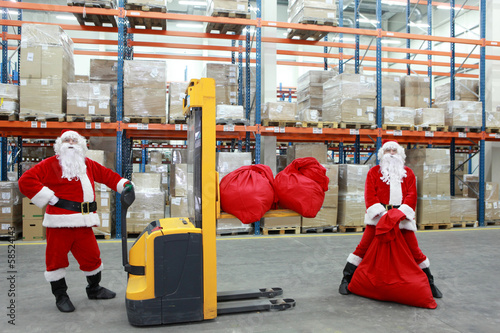 Photo: two santa clauses workers at work in large storehouse two santa clauses workers at work in large storehouse