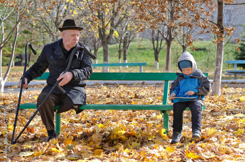 Photo: Elderly handicapped man watching a young boy Elderly handicapped man watching a young boy