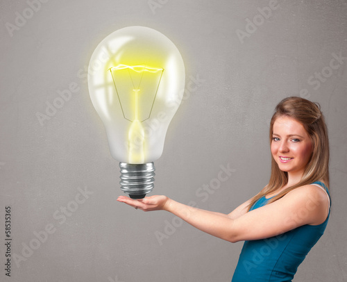 Photo: Beautiful lady holding realistic 3d light bulb Beautiful lady holding realistic 3d light bulb