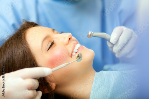 Photo: Female patient having a treatment at the dentist Female patient having a treatment at the dentist