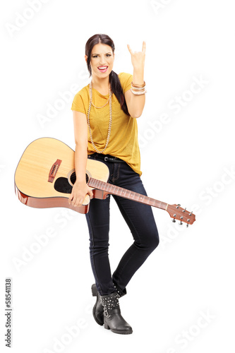 Photo: Female holding an acoustic guitar and giving rock and roll sign Female holding an acoustic guitar and giving rock and roll sign