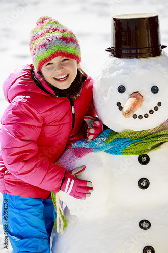 Photo: Winter fun, happy kid playing with snowman Winter fun, happy kid playing with snowman