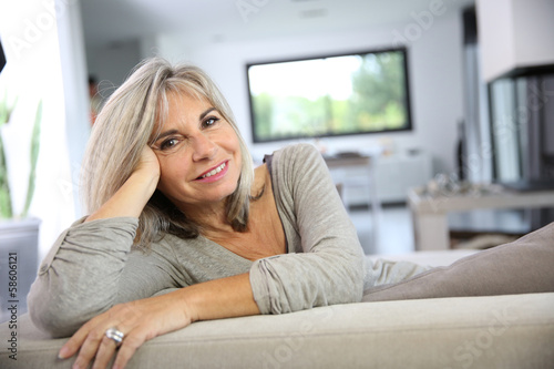 Photo: Mature woman relaxing at home in sofa Mature woman relaxing at home in sofa