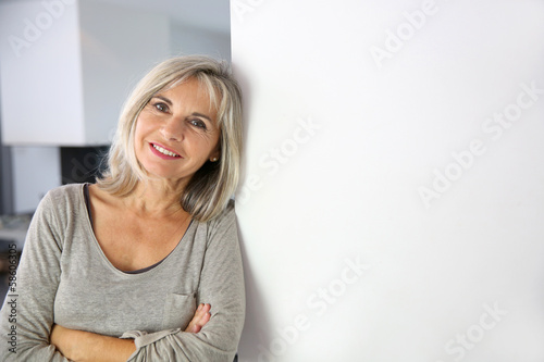 Photo: Senior woman standing against white wall Senior woman standing against white wall