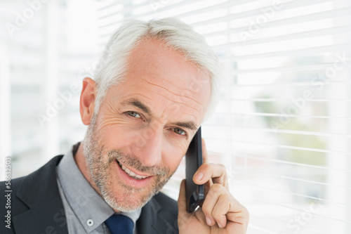 Photo: Close-up of smiling mature businessman using cellphone Close-up of smiling mature businessman using cellphone