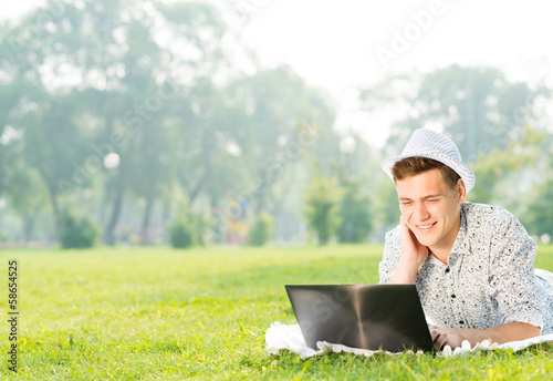 Photo: young man working in the park with a laptop young man working in the park with a laptop