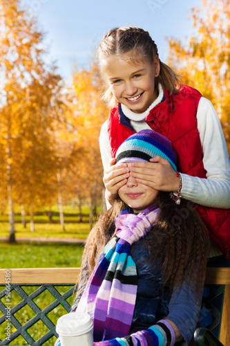 Photo: Girl covers friend face with palms and smile Girl covers friend face with palms and smile