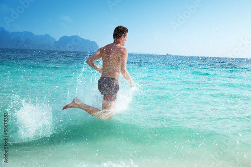 Photo: running man in water of tropical sea running man in water of tropical sea