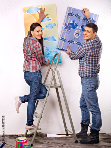 Photo: Family glues wallpaper at home. Family glues wallpaper at home.
