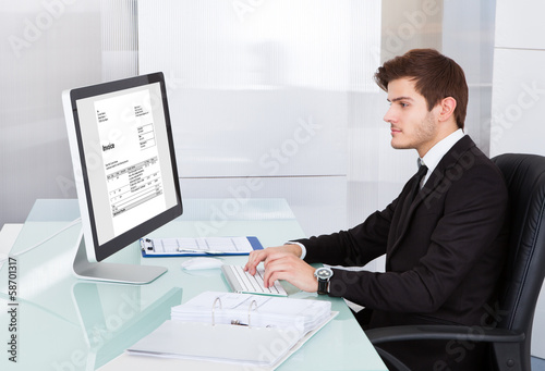 Photo: Young Businessman Using On Computer At Desk Young Businessman Using On Computer At Desk