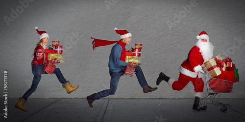 Photo: Happy people running with xmas gifts. Happy people running with xmas gifts.