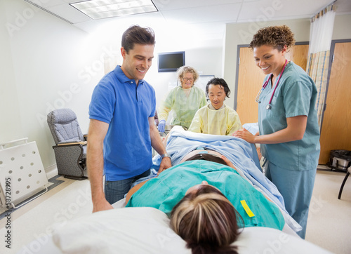 Photo: Happy Medical Team And Husband Looking At Pregnant Woman Happy Medical Team And Husband Looking At Pregnant Woman