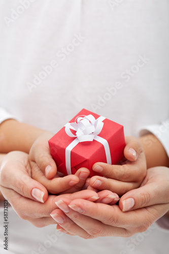 Photo: The joy of giving - small gift box in woman and child hands The joy of giving - small gift box in woman and child hands