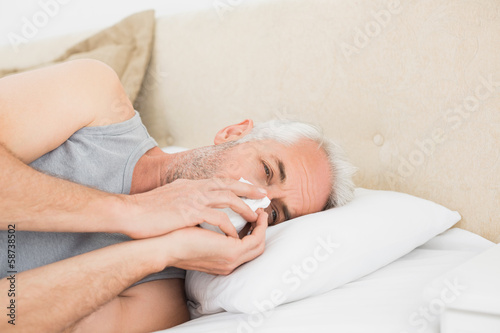 Photo: Close-up of a mature man suffering from cold in bed Close-up of a mature man suffering from cold in bed
