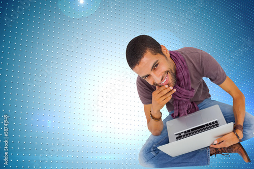 Photo: Composite image of thoughtful man sitting on floor using laptop Composite image of thoughtful man sitting on floor using laptop