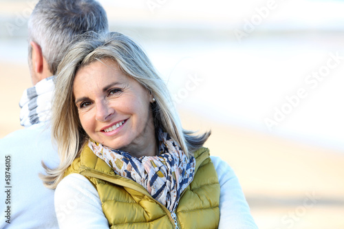 Photo: Senior woman relaxing with husband by the beach Senior woman relaxing with husband by the beach