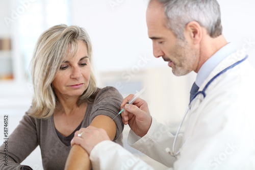 Photo: Doctor injecting vaccine to senior woman Doctor injecting vaccine to senior woman