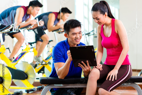 Photo: Asian personal trainer with woman in fitness gym Asian personal trainer with woman in fitness gym