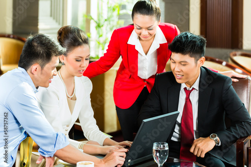 Photo: Asian business people at meeting in hotel lobby Asian business people at meeting in hotel lobby