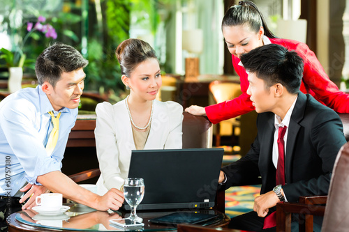 Photo: Asian business people at meeting in hotel lobby Asian business people at meeting in hotel lobby