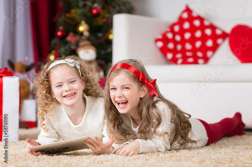 Photo: Cute girls playing in Christmas decorated room Cute girls playing in Christmas decorated room