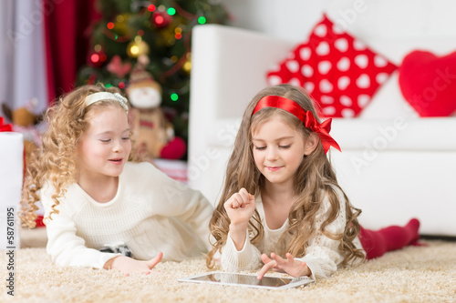 Photo: Cute girls playing in Christmas decorated room Cute girls playing in Christmas decorated room