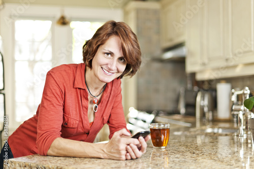 Photo: Woman using cell phone at home Woman using cell phone at home
