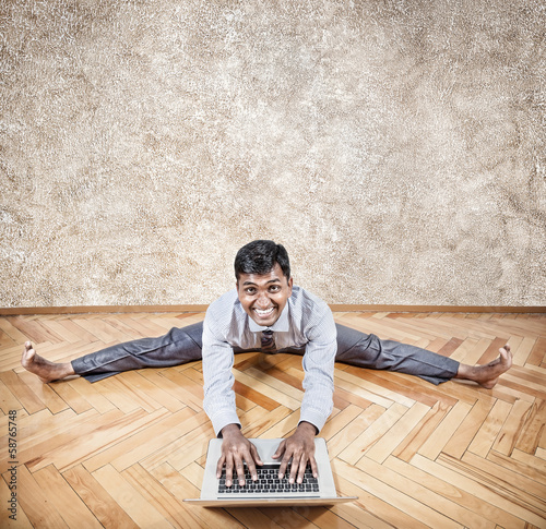 Photo: Indian man doing yoga with laptop Indian man doing yoga with laptop