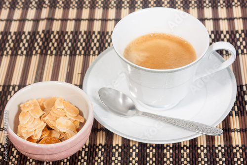 Photo: a cup of coffee with almond cookie on bamboo mat a cup of coffee with almond cookie on bamboo mat