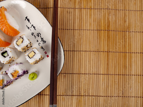 Photo: Fresh sushi and sashimi on a plate with chopsticks Fresh sushi and sashimi on a plate with chopsticks