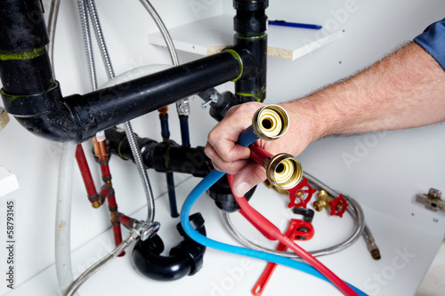 Photo: Hands of Plumber with a wrench. Hands of Plumber with a wrench.