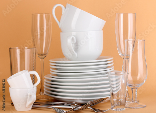 Photo: Clean white dishes on beige background Clean white dishes on beige background