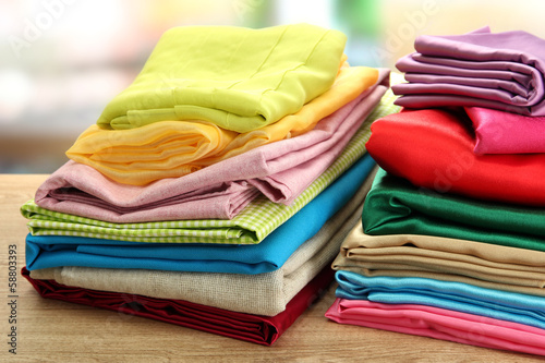 Photo: heap of cloth fabrics on wooden table heap of cloth fabrics on wooden table