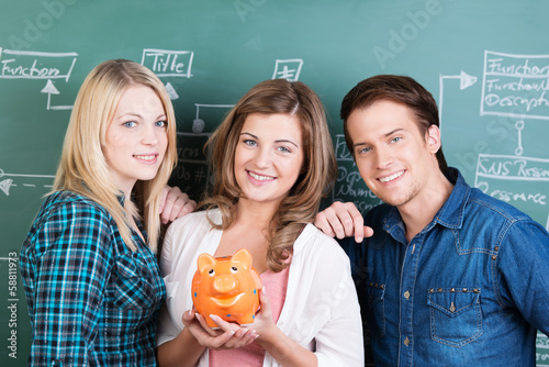Photo: drei schüler halten sparschwein in der hand drei schüler halten sparschwein in der hand
